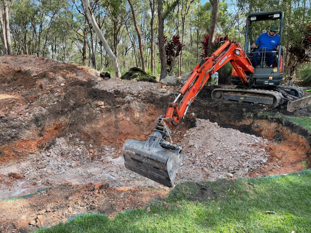 Excavation of soil on a Burbank Queensland pond project, with earth being reused on site to build elevation for a future twin waterfall system.