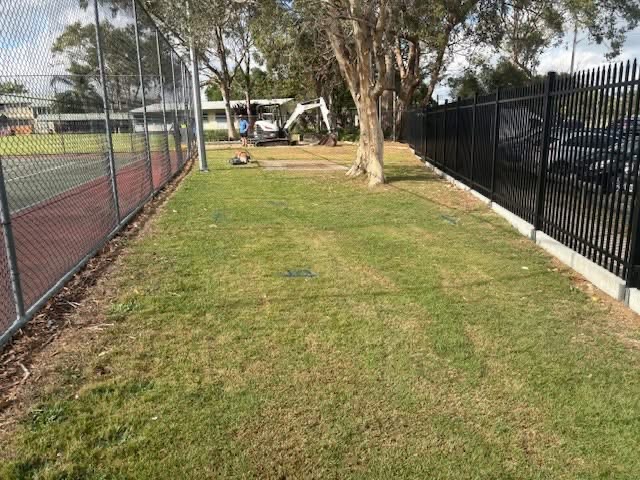 Grassed dead space with concrete pathways at Kallangur State School before pond and water feature construction