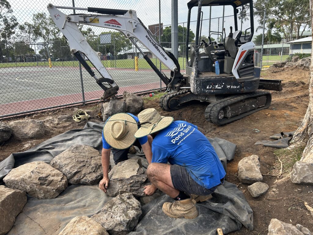 Mark and Sean positioning large rock during pond and stream construction at Kallangur State School