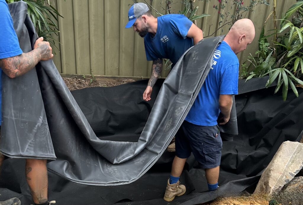 Pond Works team installing EPDM pond liner during the construction of a new ecosystem pond in South East Queensland.
